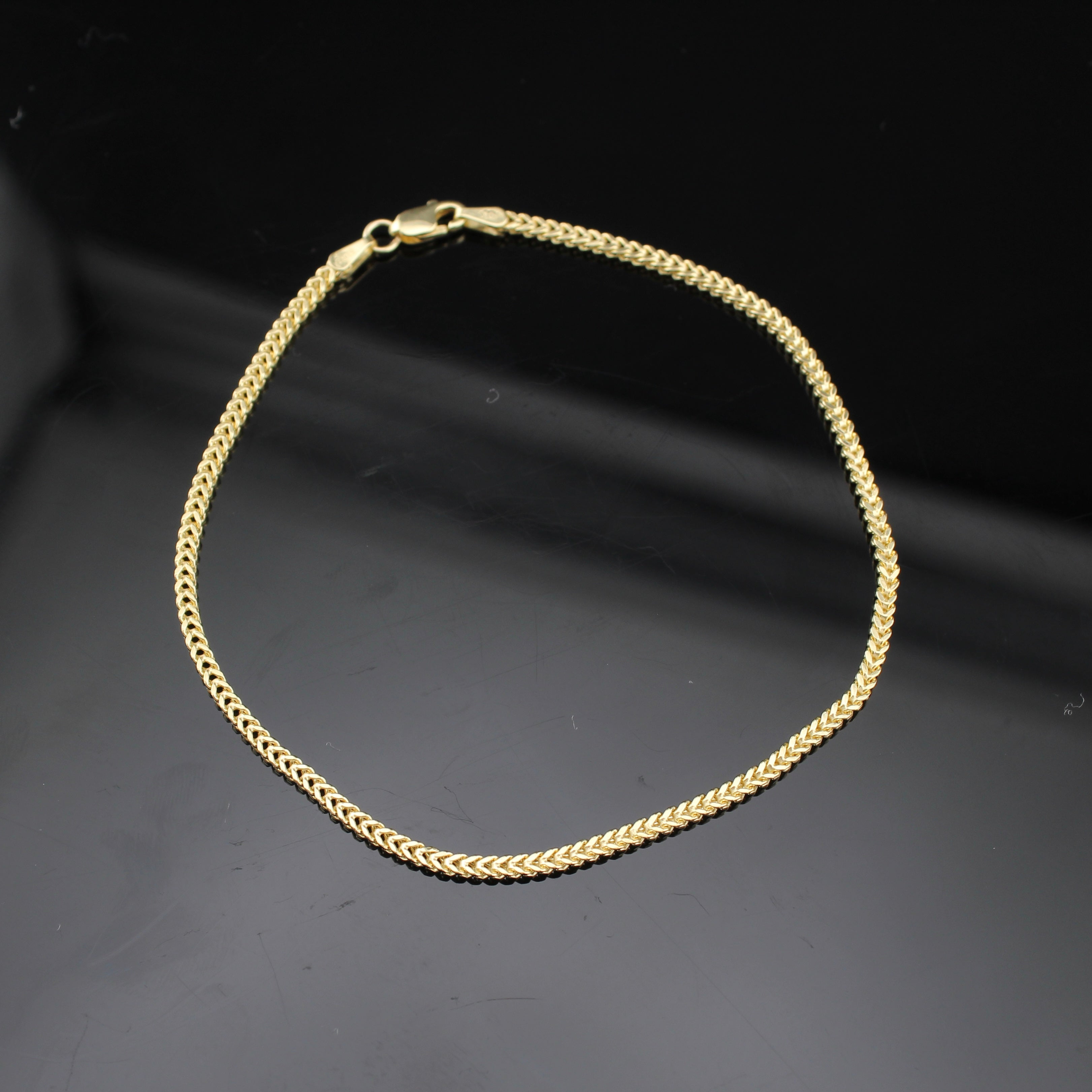Gold chain bracelet on a dark background