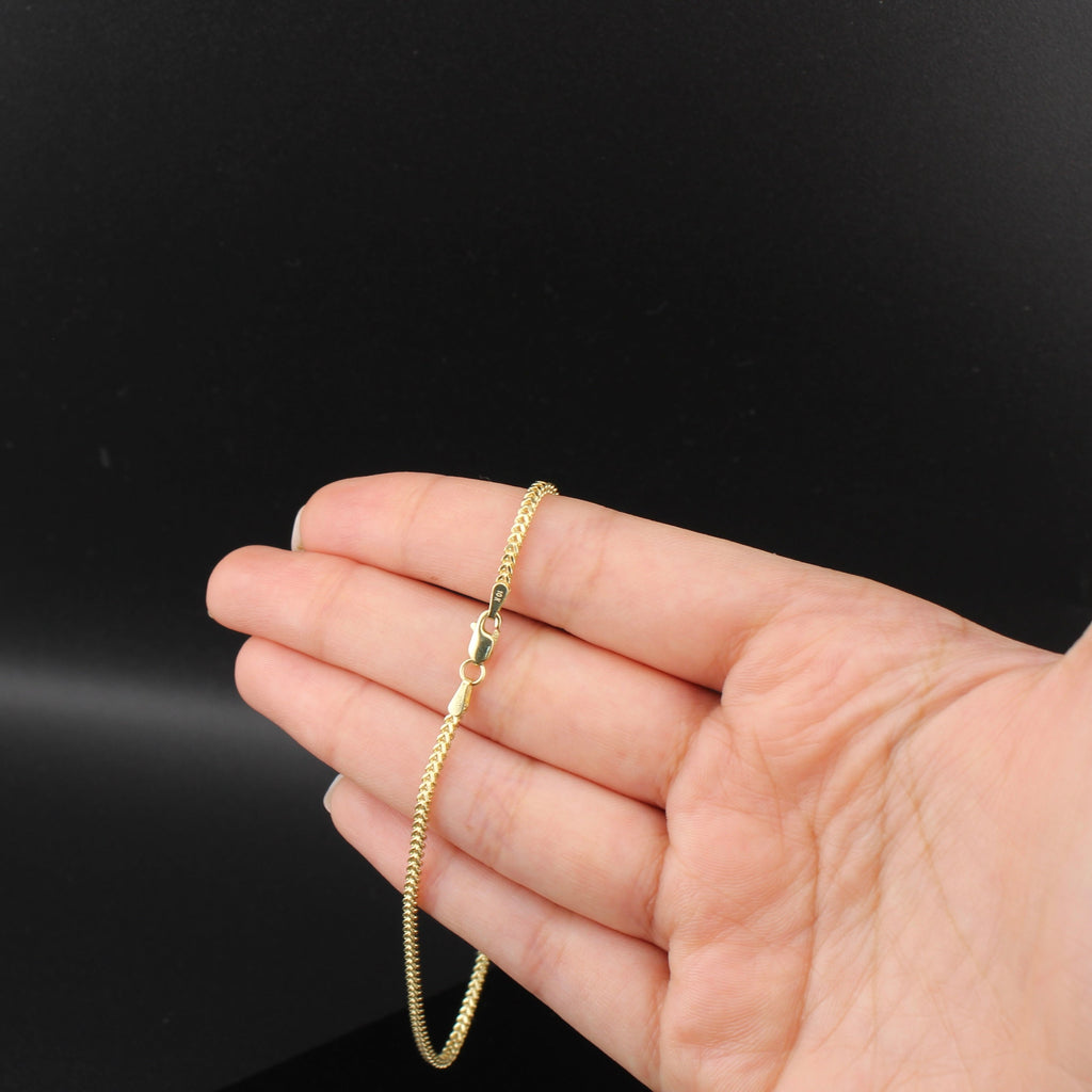Gold bracelet on a hand against a black background