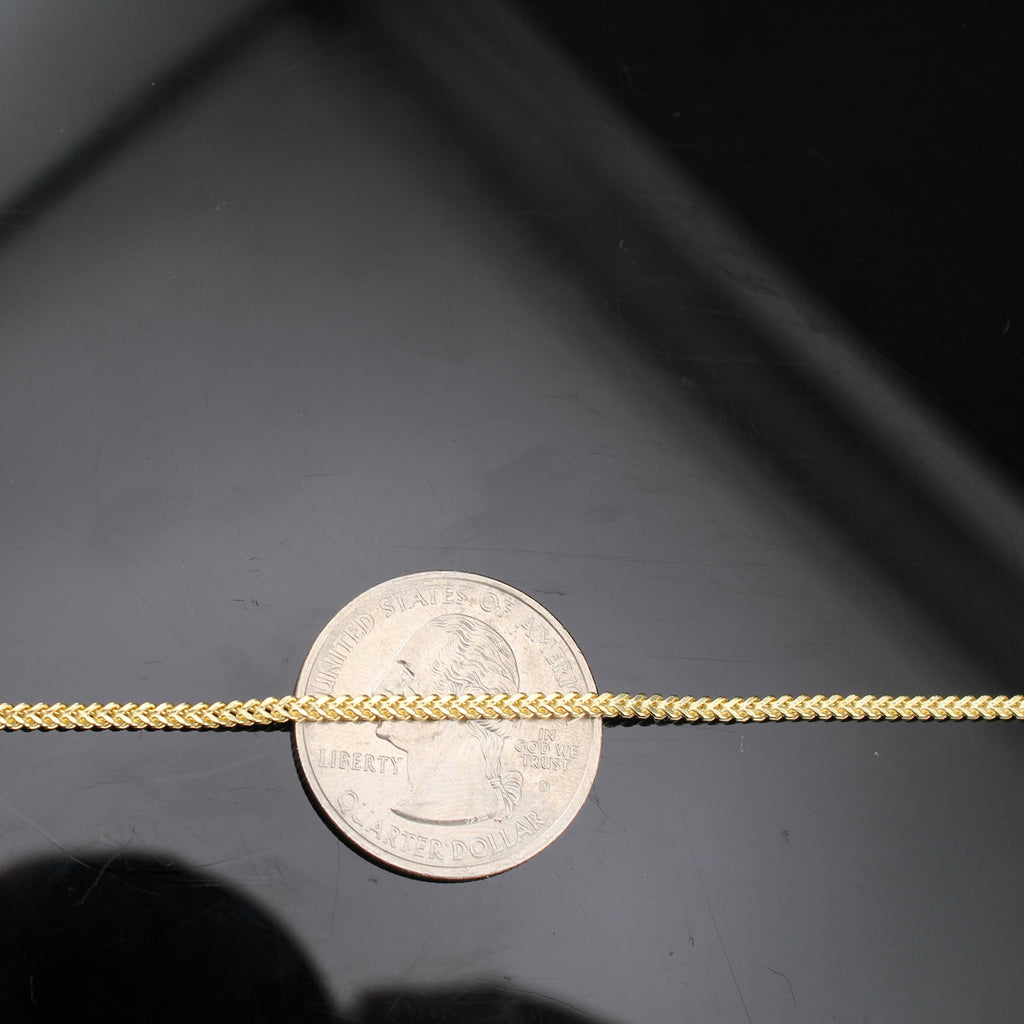 Gold chain next to a silver dollar coin on a black background