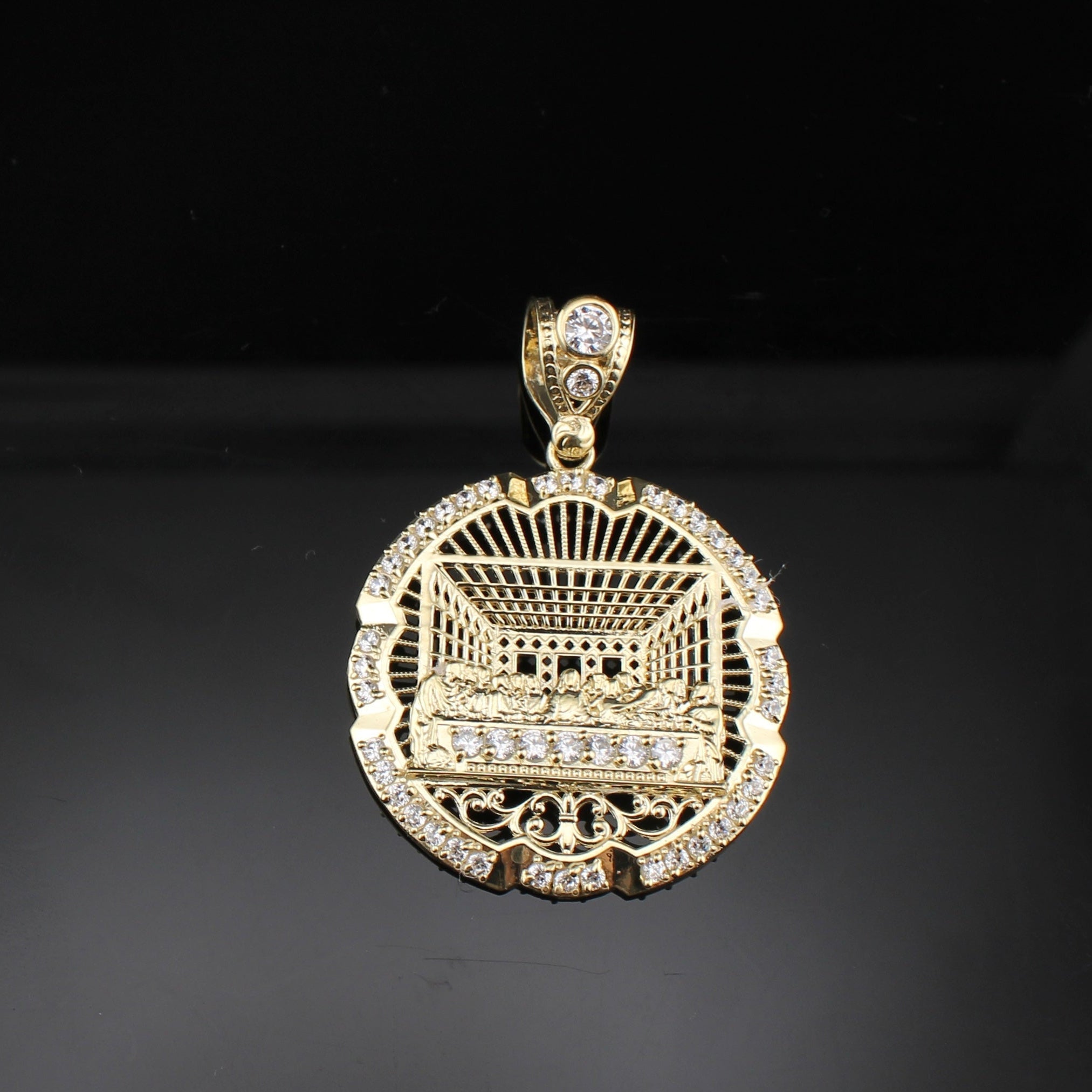 Gold pendant with intricate design and clear stones on a dark background